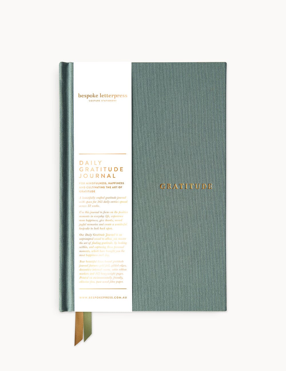 Flat lay of the Bespoke Letterpress Gratitude Journal in Seaglass. The hardcover journal features a textured sea-green cloth cover with the word "GRATITUDE" elegantly stamped in gold foil, accompanied by a branded paper wrap detailing the product's purpose and design.