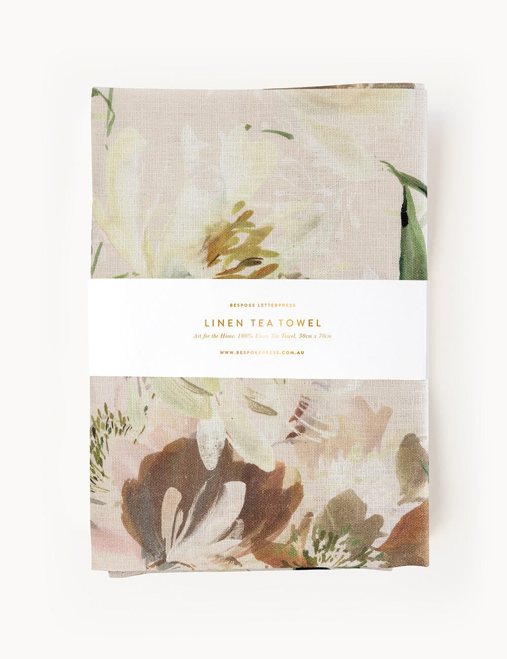 Peony linen tea towel folded in packaging, featuring painterly floral artwork in soft blush, ivory, and earthy green tones on 100% flax linen.